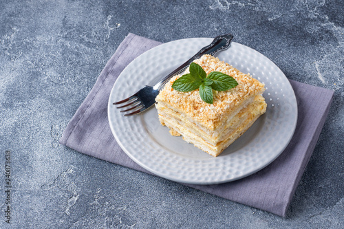 Layered cake with cream Napoleon millefeuille vanilla slice with mint on dark background.