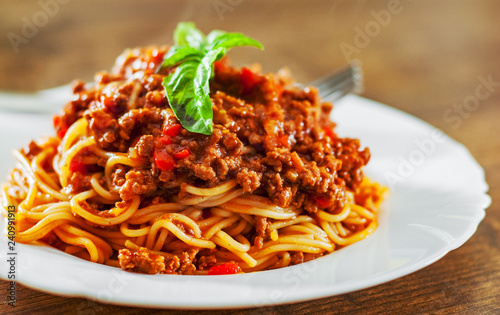 Traditional pasta spaghetti bolognese in white plate on wooden table background