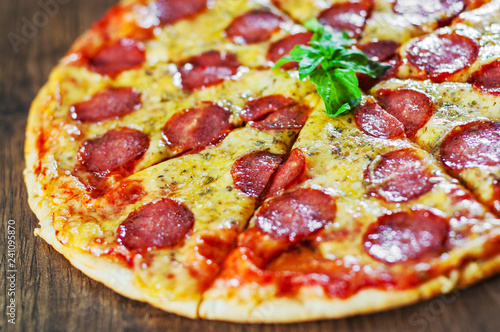 Pepperoni Pizza with Mozzarella cheese, salami, Tomato sauce, pepper, Spices and Fresh Basil. Italian pizza on wooden background
