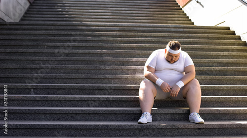 Upset man sitting alone on stairs, fighting with overweight and food addiction