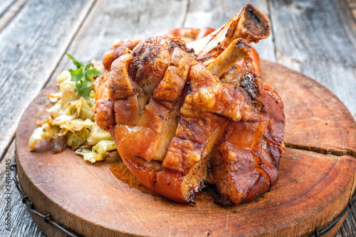 Traditionelle bayrische Schweinshaxe mit Sauerkraut und Breze als closeup auf einem Schneidebrett