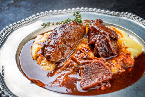 Traditional German braised veal cheeks in brown sauce with mashed potatoes as closeup on a pewter plate