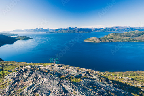 Salmon farms in Norwegian fjord, near Alta. View from high mountain peak at sunny day.