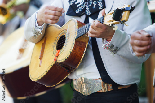 Mexican mariachi with white traditional costumes playing the vihuela at a party