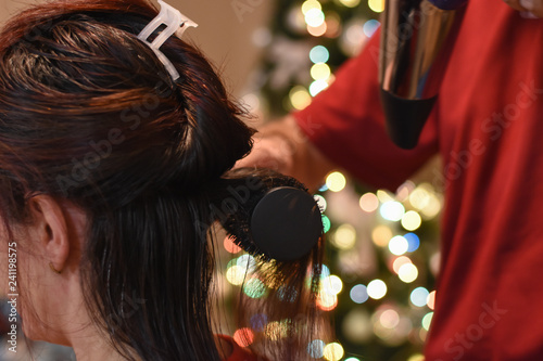 Hairdresser drying long hair with hair dryer. Making hairstyle for Christmas holidays. Concept of hair drying, barber salon, female stylist