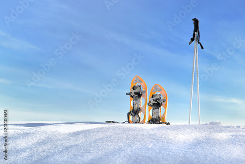 snowshoes and sticks on the snow under blue sky