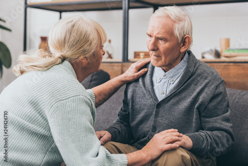 retired couple holding hands and looking at each other at home