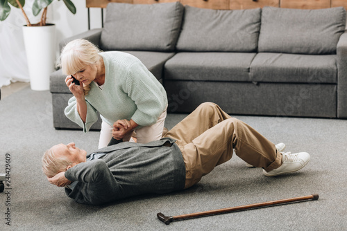 senior woman holding hand of dying old man with walking stick