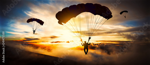 Sylwetka spadochroniarza lądowania o zachodzie słońca
