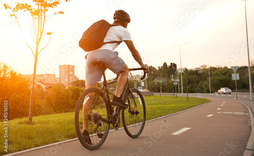Młody chłopak w zwykłym ubraniu jeździ na rowerze po mieście wieczorem
