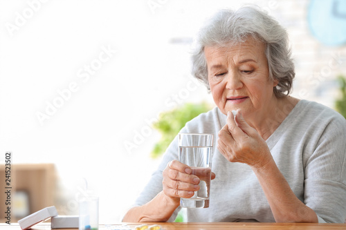 Elderly woman taking pill at home