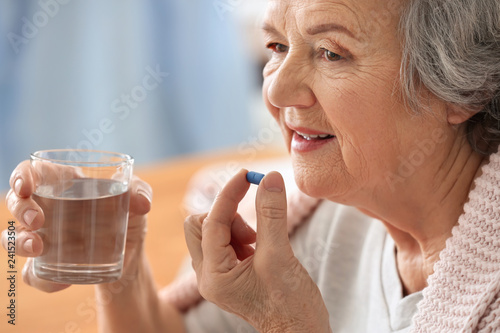 Elderly woman taking pill at home