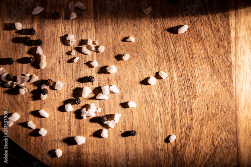 Sól kuchenna. Kompozycja kryształków soli i ziaren pieprzu na drewnianym blacie.