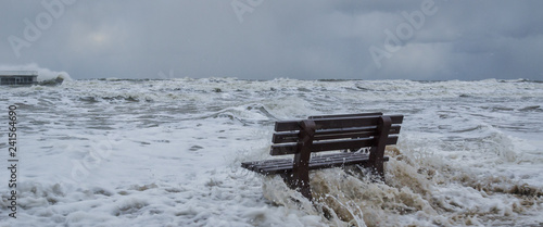 STORM AT SEA - A bench flooded by storm waves on a sea beach in Kolobrzeg 