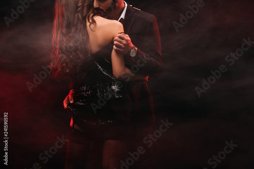 cropped view of passionate couple hugging in red smoky room