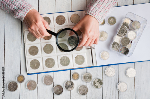 Woman looks at the coins through a magnifying glass