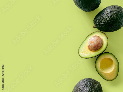 Fresh organic hass avocados on a green background, top view with copy space