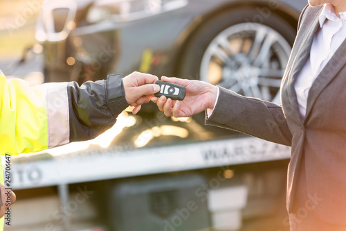Cropped image of tow truck driver giving car key to businesswoman