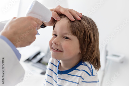 Cropped image of doctor measuring temperature of boy with infrared thermometer at hospital