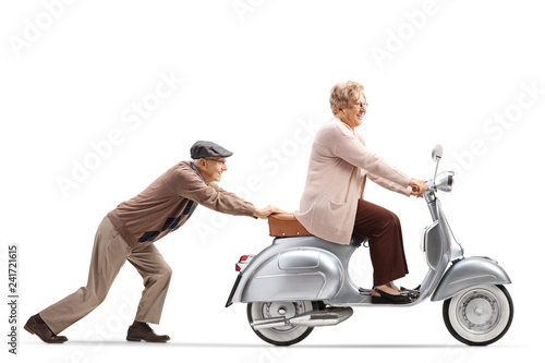 Senior man pushing a smiling senior woman riding a vintage scooter