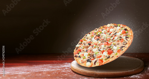 classic pizza on a dark wooden table background and a scattering of flour. pizza restaurant menu concept