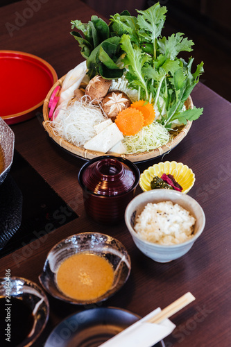 Sukiyaki vegetables set including cabbage, false pak choi, carrot, shiitake, enokitake and tofu in bamboo basket.