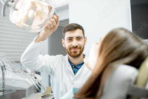 Dentist preparing for the medical examination with young woman patient in the dental office