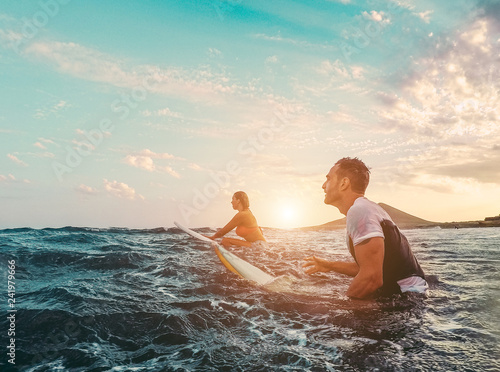 Fit couple surfing at sunset