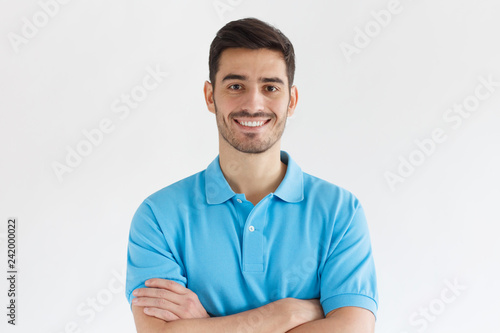 Close up portrait of young smiling handsome guy in blue polo shirt, isolated on gray background