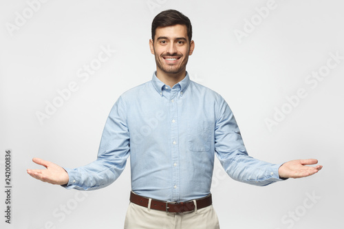 Friendly businessman with welcoming gesture isolated on gray background