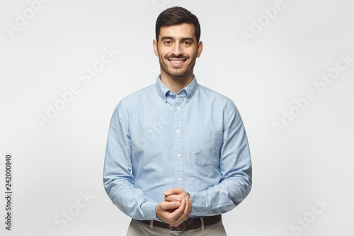 Handsome business man isolated on gray background, standing and showing positive smile to camera, looking confident