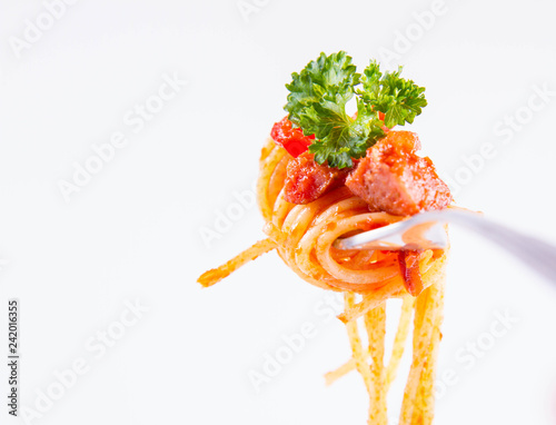 Spaghetti with sauce decorated with parsley on a fork on a white background