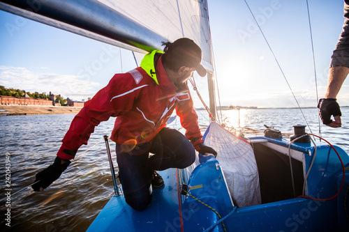 Beautiful inspiring shot of action adventure of sailor or captain on yacht or sailboat attaching big mainsail or spinnaker with ropes on deck of boat, sunny summer adventure lifestyle