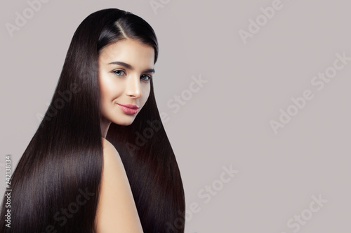 Haircare concept. Beauty brunette woman with long straight healthy hair on pink