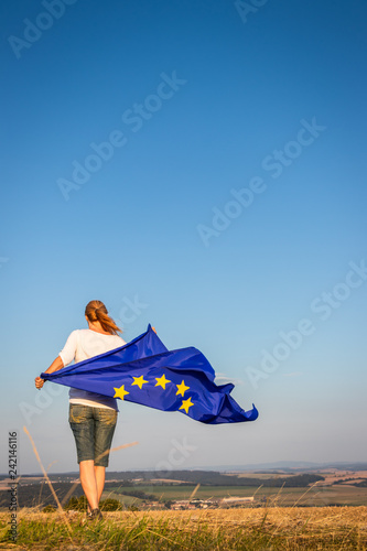 EU flag in female hands. Woman holding waving European Union flag against blue sky