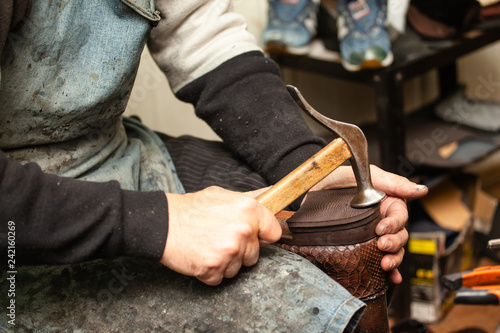 close-up of hands male shoemaker repairing shoes by nailing a heel