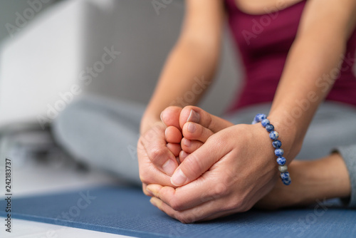 Yoga stretching woman on exercise mat at home. Seated butterfly leg stretch holding soles of feet together with hands.