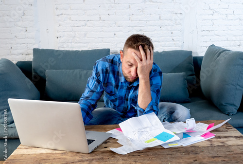 Angry man paying bills managing finances feeling desperate and hopeless with too much debts