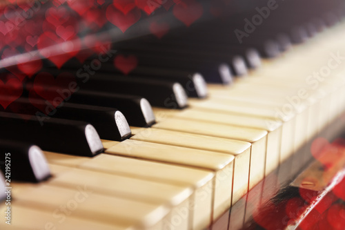 Close-up of old piano keyboard, selective focus, soft toning. Valentine's day background, vintage piano and bokeh hearts