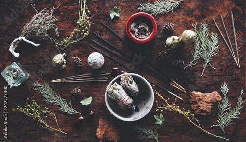 Various air element objects to use in witchcraft and wicca on a witch's altar filled with evergreens dried herbs sage incense sticks for smoke cleansing
