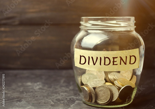 Glass jar with the word Dividend. A dividend is a payment made by a corporation to its shareholders as a distribution of profits. Concept business finance and investment. Saving money. Dividend tax