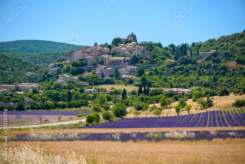 City of Saint-Saturnin-les-Apt on the hill with lavender fields in valley on summer day. Provence, France