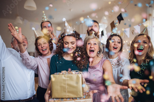 A portrait of multigeneration family with presents on a indoor birthday party.