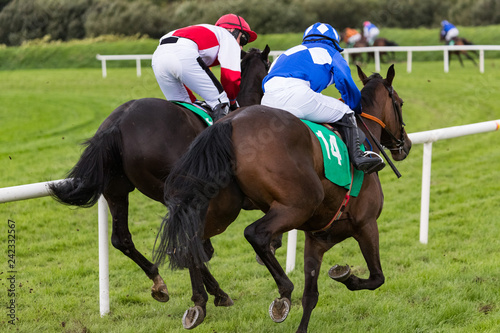 Two race horses and jockeys galloping for position on the race track