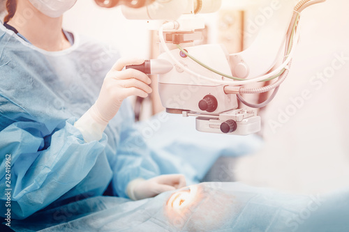 Doctor examines fundus in microscope, patient under sterile cover. Laser vision correction lasik