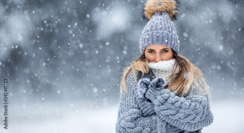 Portrait of young beautiful woman in winter clothes and strong snowing.