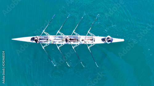 Aerial drone top down view of sport canoe operated by team of young women in emerald clear sea