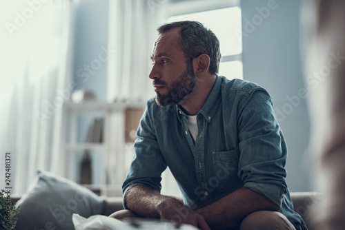 Waist up of bearded man thoughtfully looking away