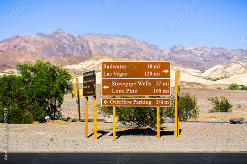 Posted road directions and distances close to the Furnace Creek Visitor Center; desert and mountains landscape in the background; Death Valley National Park, California