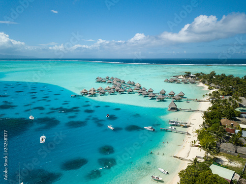 Luksusowe wille nad wodą z palmami kokosowymi, błękitną laguną, białą piaszczystą plażą na wyspie Bora Bora, Tahiti, Polinezja Francuska